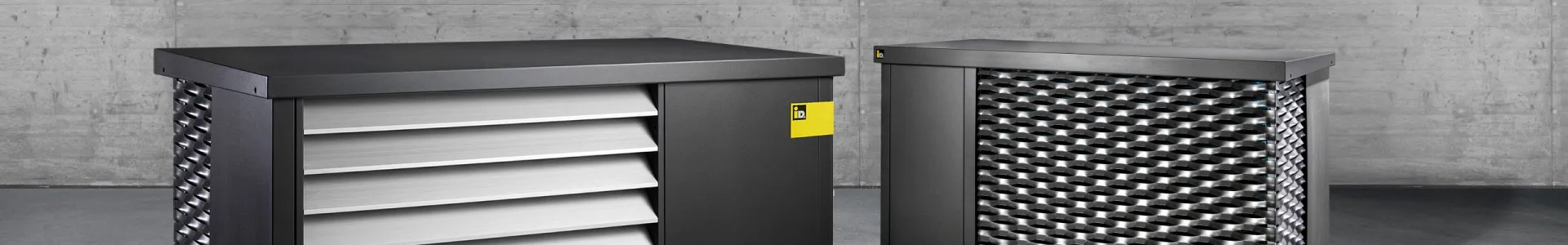 Zwei moderne Luftwärmepumpen von iDM Energiesysteme vor Betonwand – technologische Spitzenprodukte für emissionsfreie Heiz- und Kühllösungen „Made in Austria“.