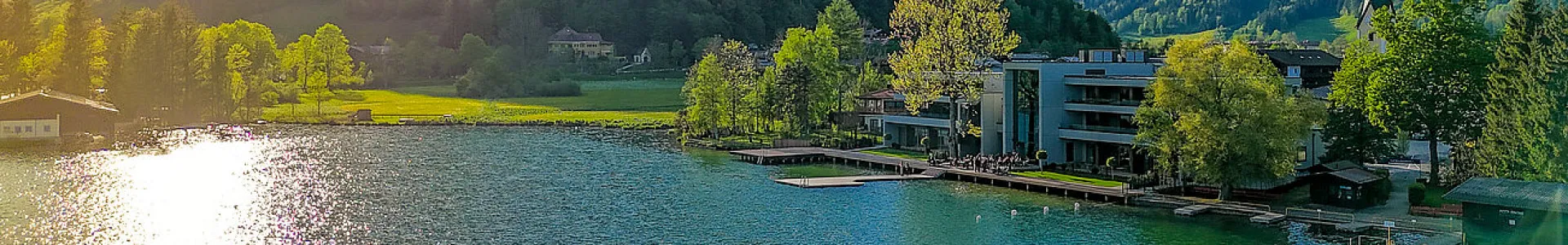Blick auf das Pletzer Resort Walchsee am Seeufer, eingebettet in die Natur mit moderner Architektur und großzügiger Terrasse – Sinnbild für aktive Erholung, regionale Verwurzelung und nachhaltige Gastfreundschaft.