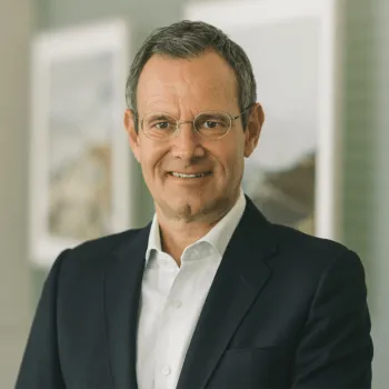 Porträt von Manfred Pletzer, Geschäftsführer der Pletzer Immobilien, mit Brille und Anzug in modernem Büroambiente.
